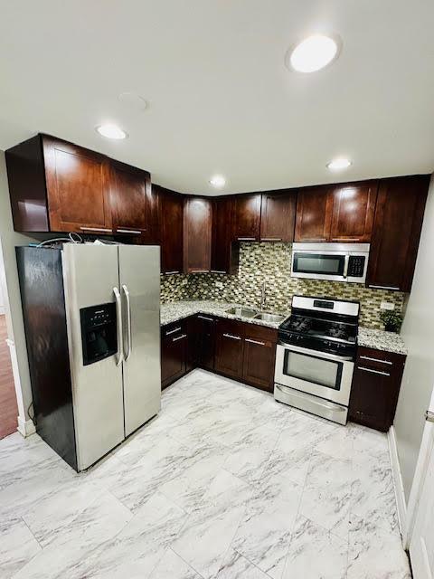 kitchen featuring marble finish floor, appliances with stainless steel finishes, decorative backsplash, and a sink