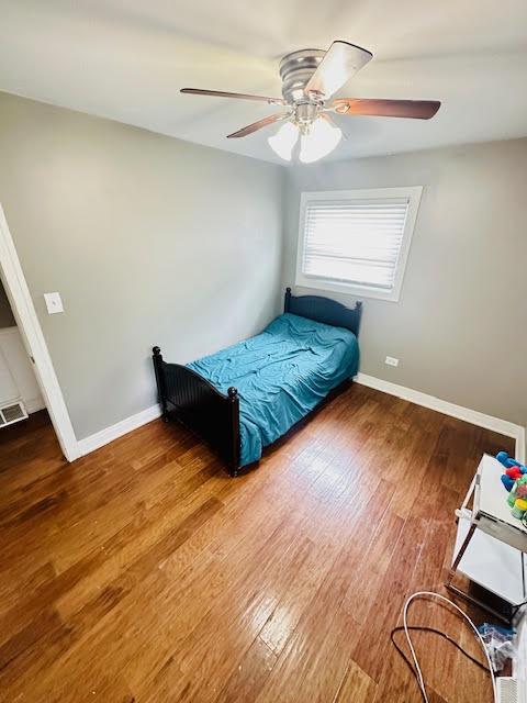 bedroom featuring visible vents, ceiling fan, baseboards, and wood finished floors