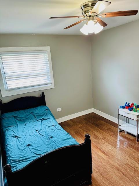 bedroom with multiple windows, baseboards, and wood finished floors