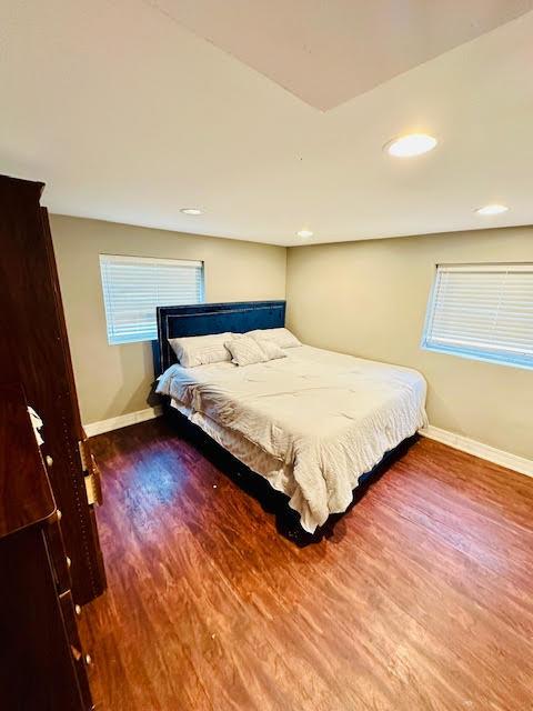 bedroom with baseboards, wood finished floors, and recessed lighting