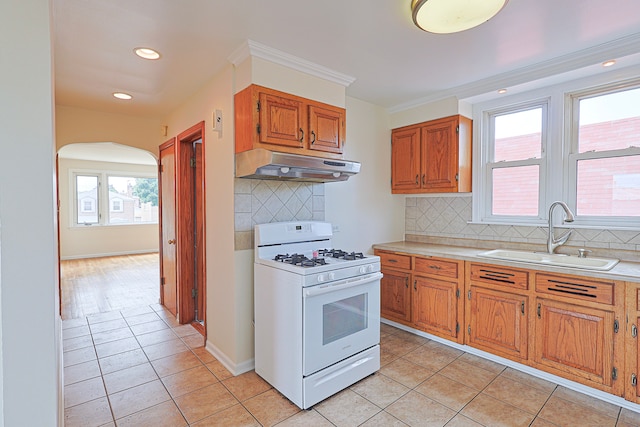 kitchen featuring sink, backsplash, light tile patterned floors, and white gas range oven