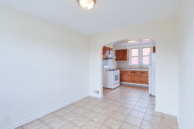 kitchen featuring decorative backsplash, sink, white appliances, and light tile patterned floors