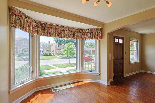 foyer entrance featuring wood-type flooring, a wealth of natural light, and ornamental molding