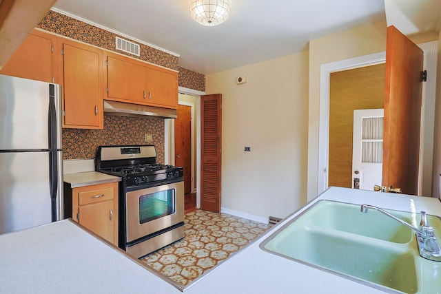 kitchen featuring backsplash, gas range, range hood, refrigerator, and sink