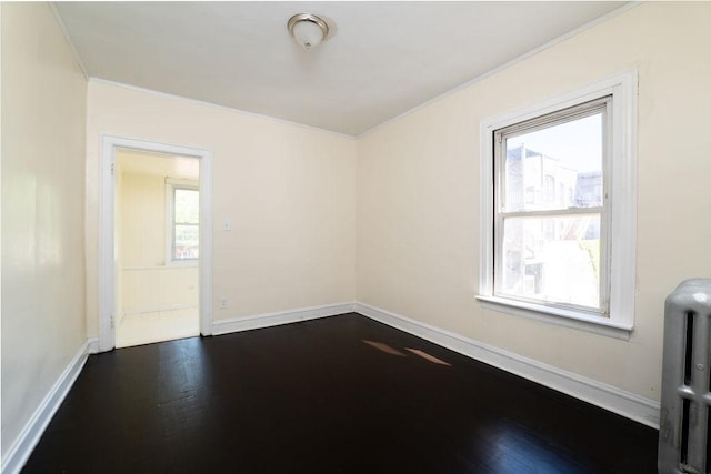 spare room featuring radiator heating unit, ornamental molding, and dark wood-type flooring