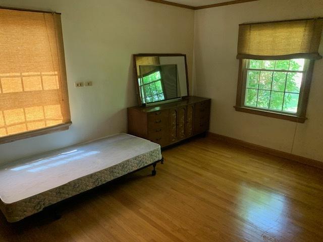 bedroom featuring wood-type flooring and ornamental molding