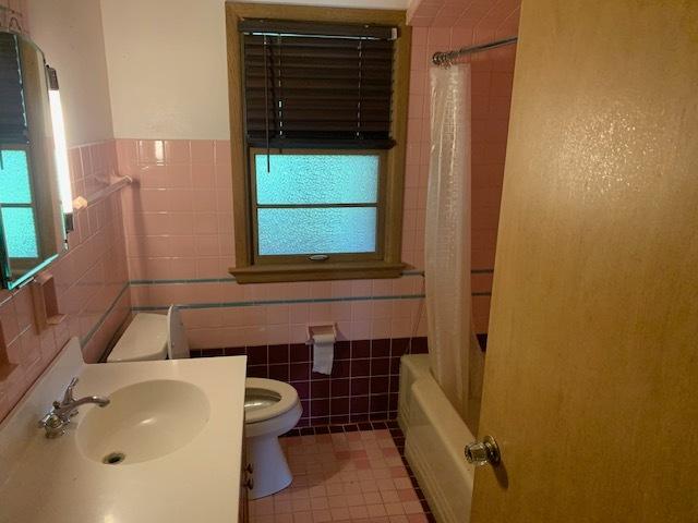 full bathroom with tile patterned floors, shower / bathtub combination with curtain, tile walls, and toilet