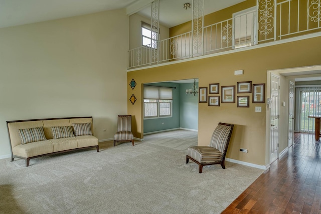 sitting room with an inviting chandelier, beam ceiling, a high ceiling, and carpet flooring