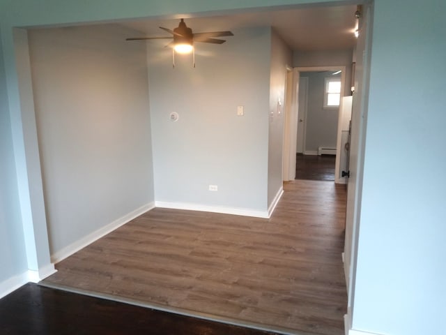 spare room featuring a baseboard heating unit, dark wood-type flooring, and ceiling fan