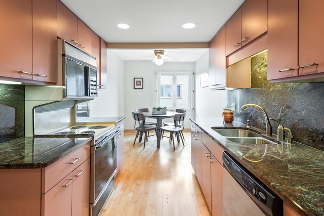 kitchen with appliances with stainless steel finishes, light hardwood / wood-style floors, sink, decorative backsplash, and ceiling fan