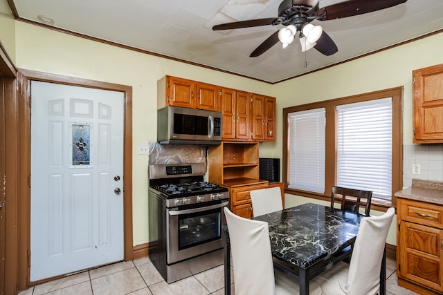 kitchen featuring appliances with stainless steel finishes, backsplash, light tile patterned floors, ceiling fan, and ornamental molding