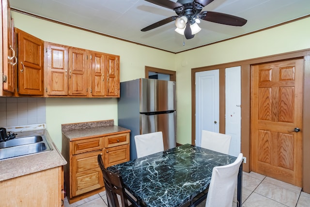 kitchen featuring ceiling fan, decorative backsplash, ornamental molding, sink, and stainless steel refrigerator