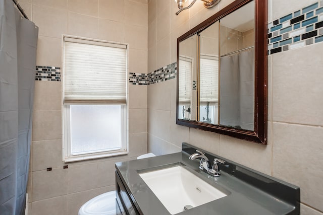 bathroom with vanity, toilet, and tile walls