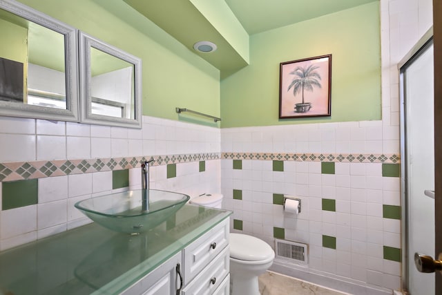 bathroom featuring tile walls, vanity, and toilet