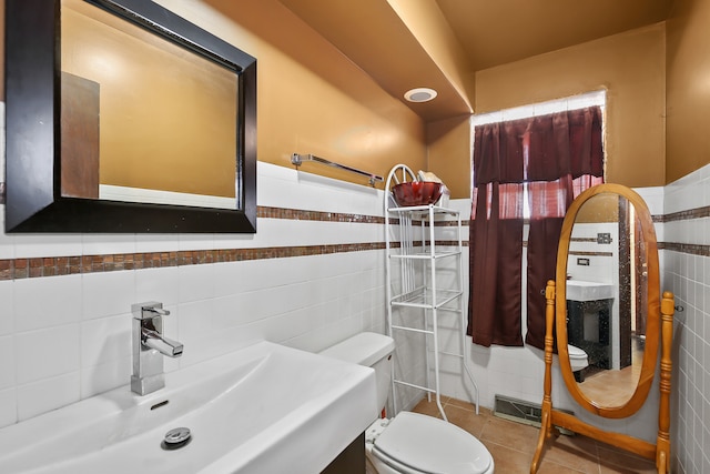 bathroom featuring toilet, sink, tile walls, and tile patterned flooring