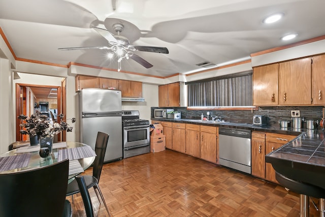 kitchen featuring appliances with stainless steel finishes, sink, dark parquet floors, ceiling fan, and decorative backsplash