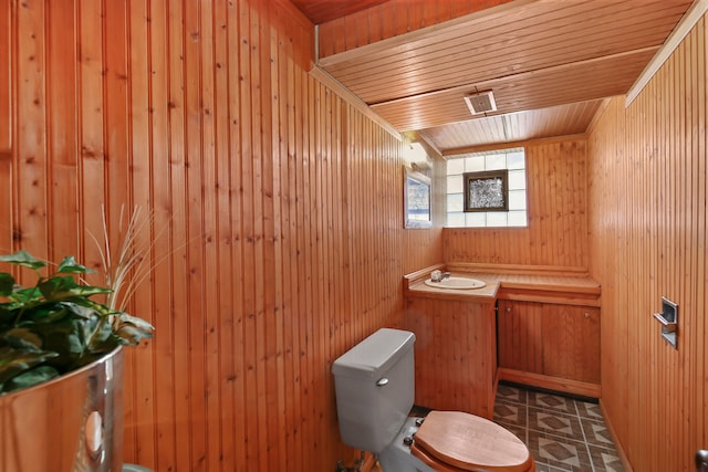 bathroom with sink, wood ceiling, toilet, and wood walls