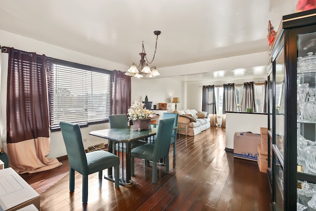 dining room with dark wood-type flooring, a notable chandelier, and a healthy amount of sunlight