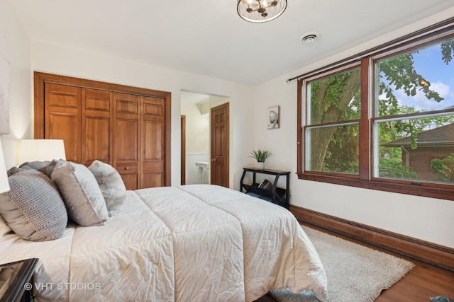 bedroom with a baseboard heating unit, baseboards, visible vents, and wood finished floors