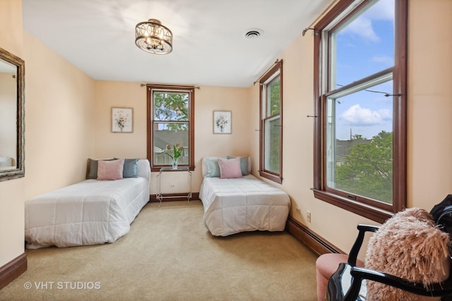 carpeted bedroom featuring a baseboard heating unit, baseboards, and visible vents