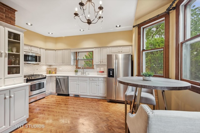 kitchen with backsplash, stainless steel appliances, light countertops, and a sink