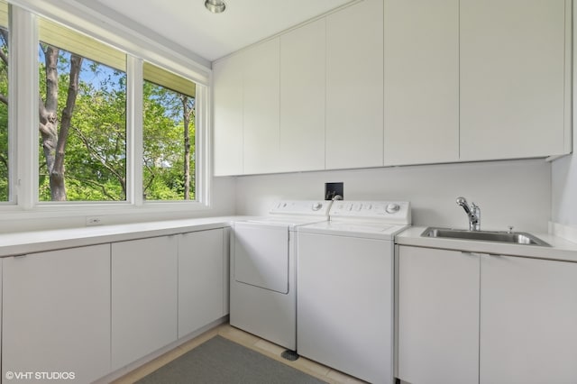 laundry area featuring cabinets, washing machine and clothes dryer, and sink