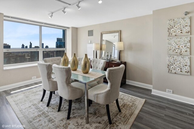 dining area with rail lighting and dark wood-type flooring