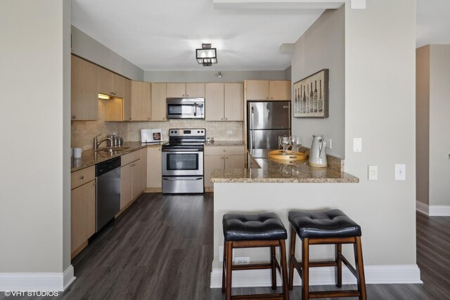 kitchen featuring dark hardwood / wood-style flooring, light brown cabinetry, backsplash, and stainless steel appliances