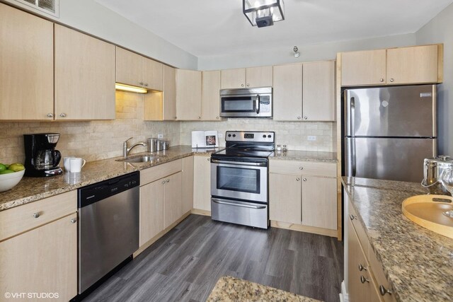 kitchen featuring dark hardwood / wood-style floors, light stone countertops, light brown cabinets, and stainless steel appliances