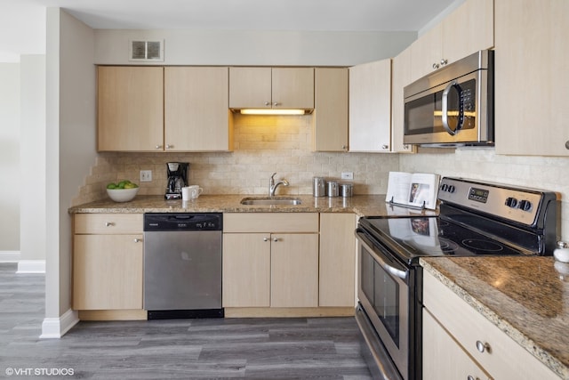 kitchen with appliances with stainless steel finishes, light stone countertops, dark wood-type flooring, and light brown cabinets