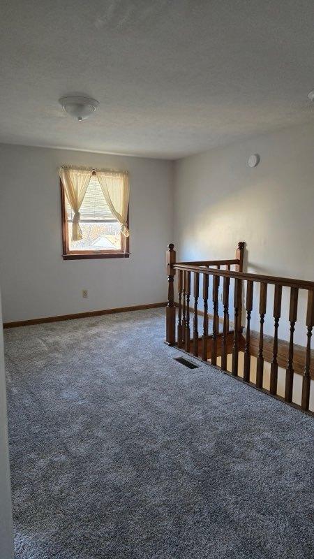 carpeted spare room with a textured ceiling