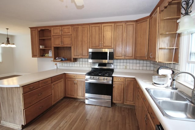 kitchen featuring pendant lighting, stainless steel appliances, sink, dark hardwood / wood-style floors, and kitchen peninsula