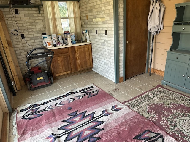 bathroom with tile patterned floors and brick wall