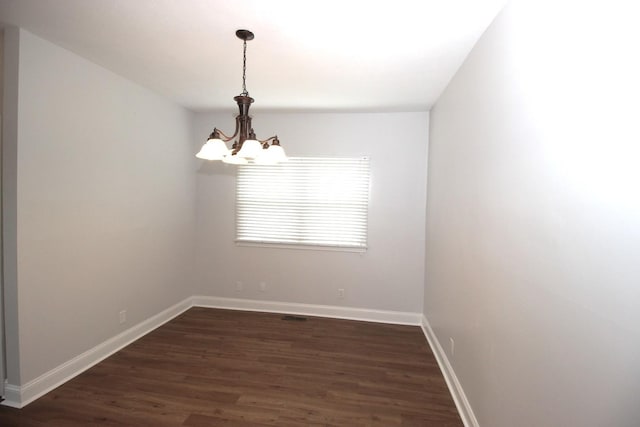 unfurnished room featuring dark hardwood / wood-style flooring and a notable chandelier