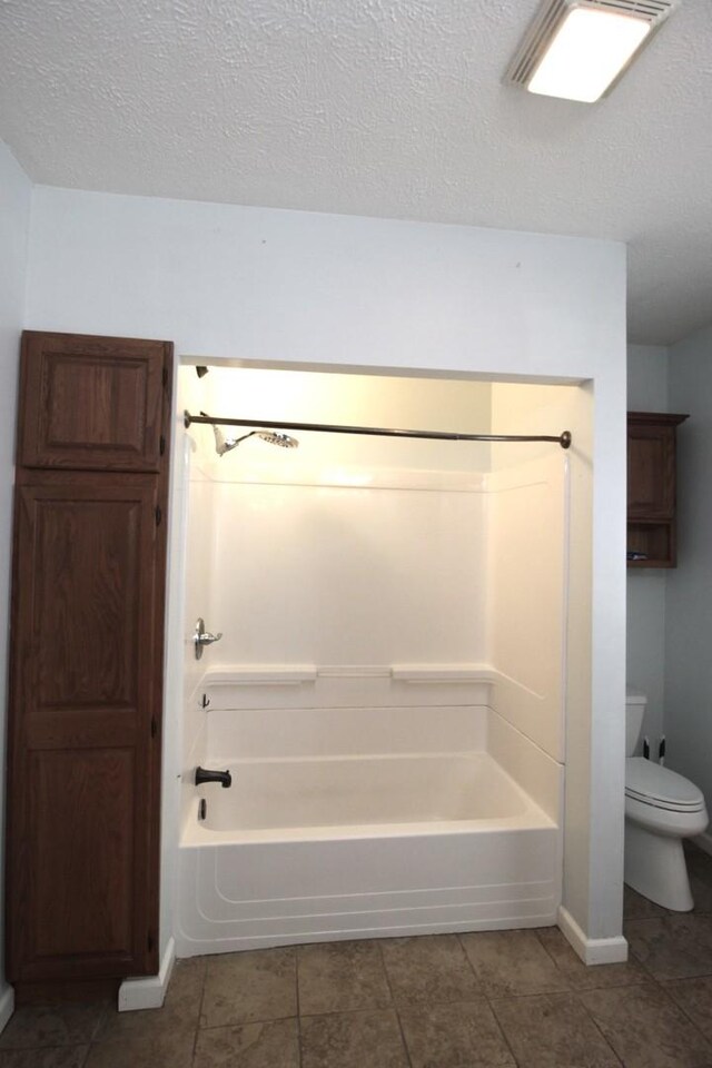 bathroom with toilet, a textured ceiling, and washtub / shower combination