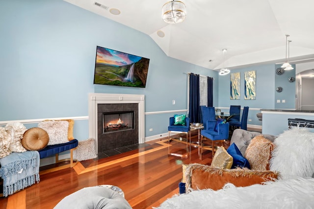 living room with wood-type flooring, lofted ceiling, and a tile fireplace