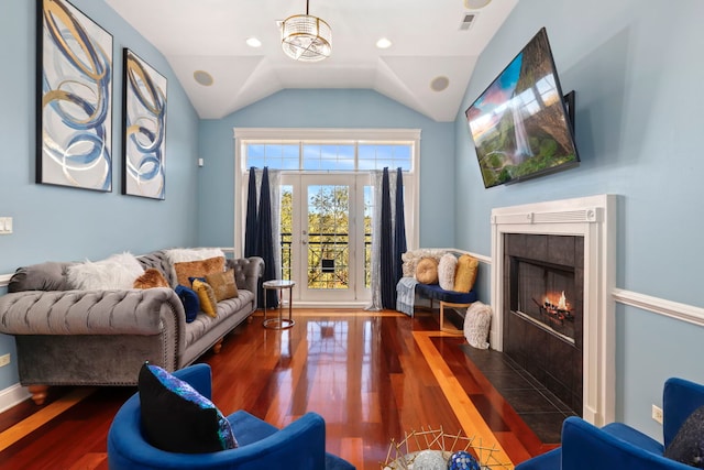 living room featuring dark wood-type flooring, a tiled fireplace, and vaulted ceiling