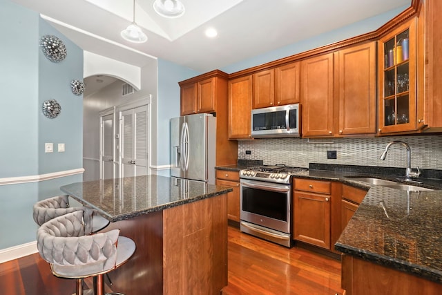 kitchen featuring stainless steel appliances, decorative backsplash, sink, and hanging light fixtures