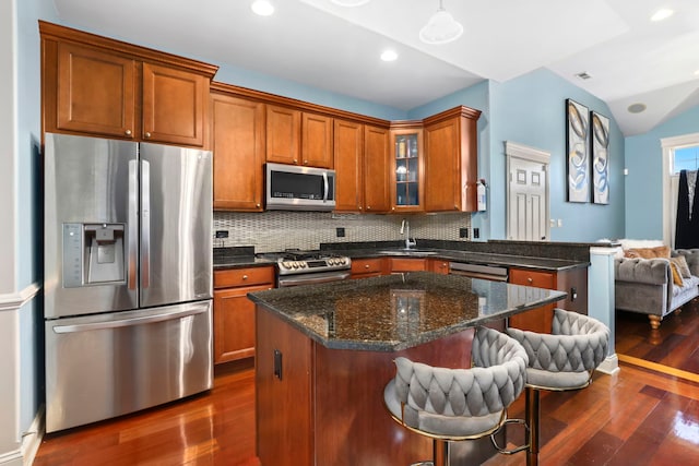 kitchen featuring backsplash, vaulted ceiling, stainless steel appliances, dark wood-type flooring, and sink