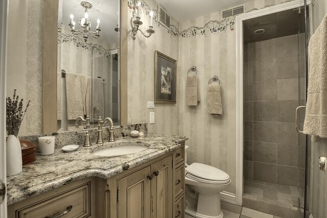 bathroom with tile patterned flooring, vanity, toilet, and an enclosed shower