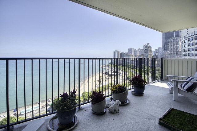 balcony featuring a view of the beach and a water view