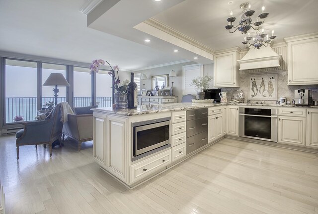 kitchen featuring ornamental molding, kitchen peninsula, light hardwood / wood-style flooring, appliances with stainless steel finishes, and an inviting chandelier