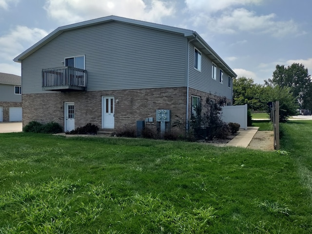 view of home's exterior featuring a balcony and a yard