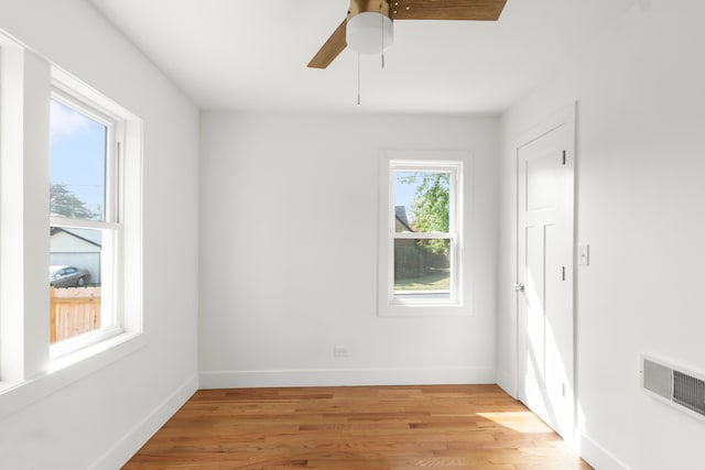 empty room with ceiling fan, a wealth of natural light, and light hardwood / wood-style flooring