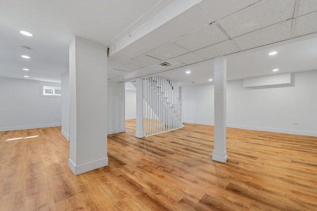 basement featuring light hardwood / wood-style floors and a paneled ceiling