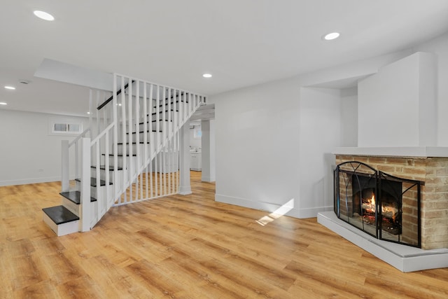 living room with a brick fireplace and light hardwood / wood-style flooring