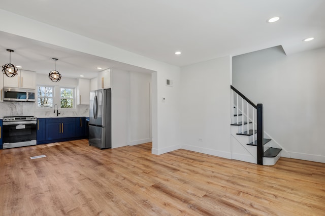 kitchen featuring light hardwood / wood-style floors, stainless steel appliances, backsplash, blue cabinetry, and sink