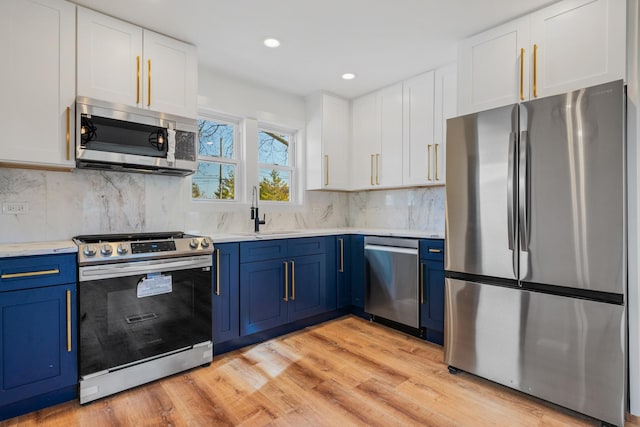 kitchen with appliances with stainless steel finishes, sink, blue cabinetry, and white cabinetry