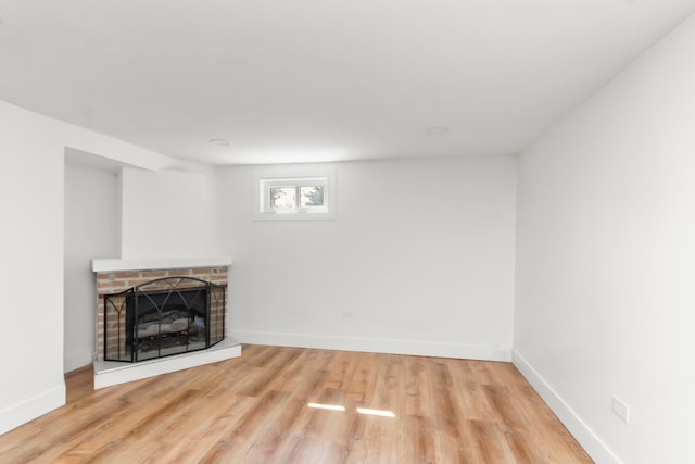 unfurnished living room with a brick fireplace and light hardwood / wood-style floors