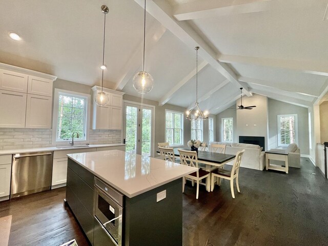 kitchen with vaulted ceiling with beams, stainless steel appliances, sink, backsplash, and dark wood-type flooring